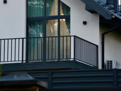 Garde-corps à barreaux droits en acier anthracite devant une grande baie vitrée de maison contemporaine
