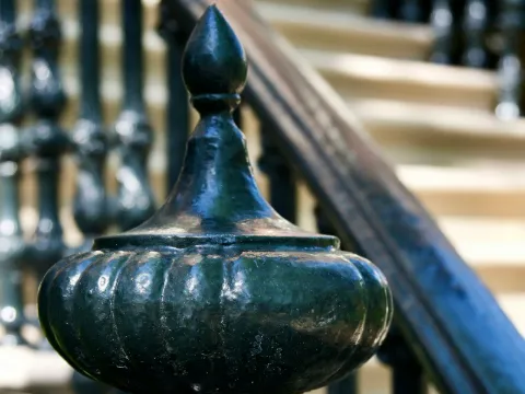 Poteau de départ à fleuron et main courante en fer noir sur les marches d'un perron