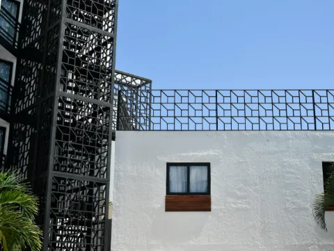 Écrans de métal noir découpés de motifs géométriques au-dessus d'un mur blanc
