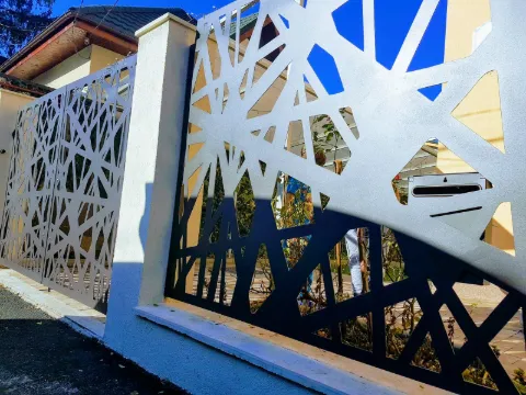 Panneaux d'acier graphite découpés au laser, motif de lignes brisées, sur un muret de villa