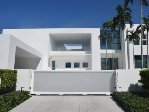 Portail coulissant plein blanc devant une villa contemporaine aux lignes épurées et aux palmiers