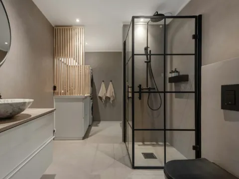 Salle de bain en béton ciré, douche à verrière noire et vasque de pierre