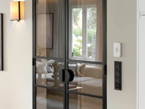 Double porte vitrée en acier noir et verre fumé ouvrant sur un salon, applique murale